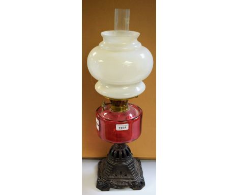 A Victorian brass oil lamp, opaque white glass shade, cranberry glass reservoir, twin burner, cast iron base, 58cm high overa