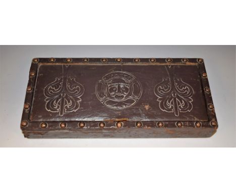 An Arts and Crafts 'antiquarian salvage' rectangular playing card box, tooled leather cover with a foliate mask flanked by ac