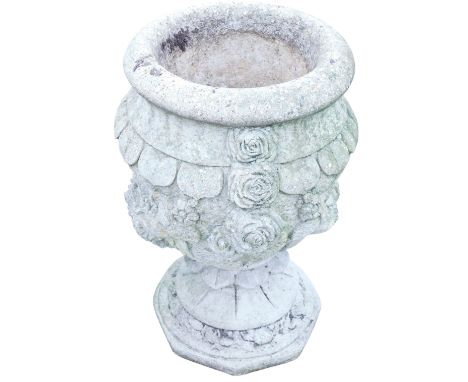 A composition stone garden urn, decorated with rose heads and other floral motifs, on a circular floral carved base, 64cm hig