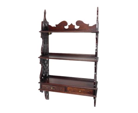 A hardwood wall shelf, with a shaped crest, two shelves, flanked by pierced sides and two drawers, 95cm high, 52cm wide.