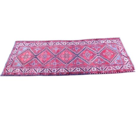 A Persian runner, with a design of lozenges with geometric devices, blue spandrels, one wide and two narrow borders.