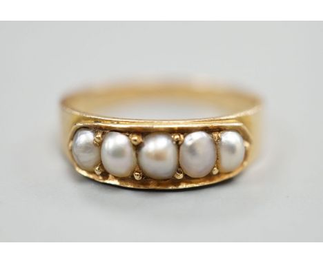 A yellow metal and graduated five stone split pearl set half hoop ring, size M, gross 3 grams.