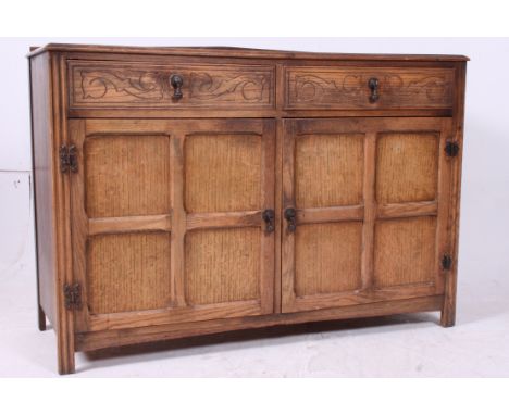 A 1930's oak Jacobean revival sideboard dresser. The qtr panel doors under 2 short drawers above. Shaped top with stage galle