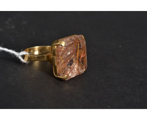 An 18ct gold cushion cut stone cocktail dress ladies ring. The inset oversized stone with inset copper. Raised over bezel mou