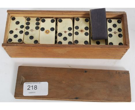 An early 20th century set of dominos having a good faux ivory panel to each set within original wooden box