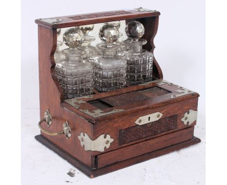 A mid-20th century tantalus containing 3x glass decanters, with secret drawer to front, containing cribbage board, various ot