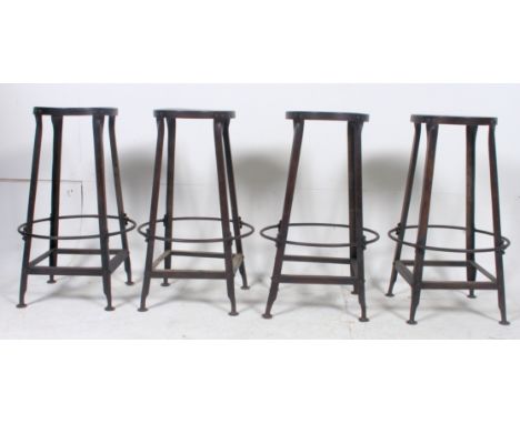 A set of 4 20th century Industrial metal machinist stools having peripheral stretchers to the base with pierced panel seats. 