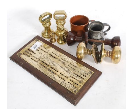 A mixed lot to include antique brass bells weights, cribbage board, pewter and cooper measures, brass and bakelite door handl