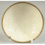 A CHINESE DING STYLE TEA BOWL, with carved floral decoration and gilt rim, 10cm diameter.