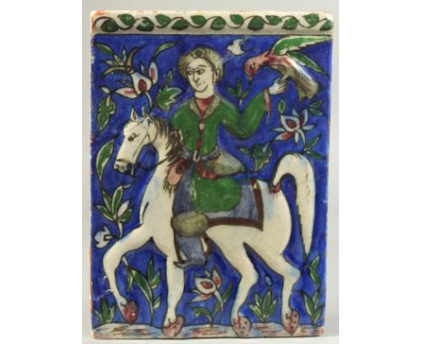 A PERSIAN QAJAR GLAZED POTTERY TILE, with a figure on horseback holding a bird aloft, 22cm x 16cm.