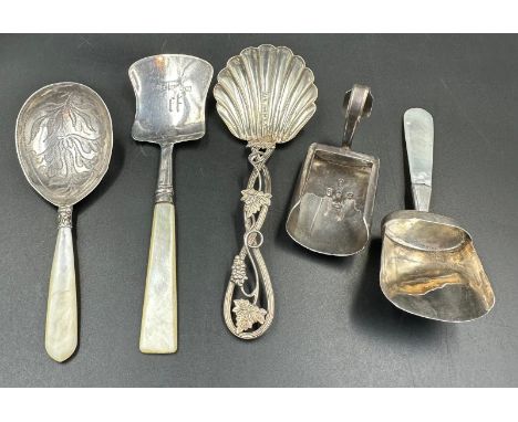 A selection of five caddy spoons and sugar shovels by various makers and styles including several with mother of pearl handle