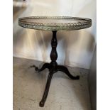 A circular oak pedestal table with galleried brass top on cast iron splayed legs