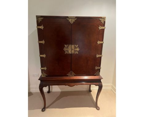 A cocktail cabinet on stand with brass banding to doors opening to reveal sliding drinks stands (H168cm Q112cm D58cm) 