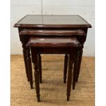 A nest of three glass top side tables with string inlay on fluted legs