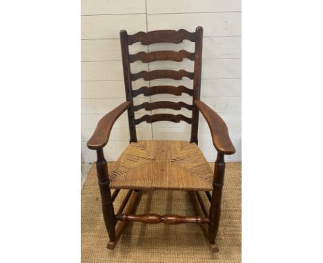 A vintage Elm ladder back rocking chair with rush seat 