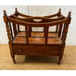A mahogany single drawer canterbury on turned supports and castors with turned finials to top