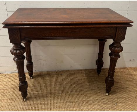 A Victorian card table, fold over top opening to reveal green baize interior on reeded legs and castors (H76cm W92cm D46cm)