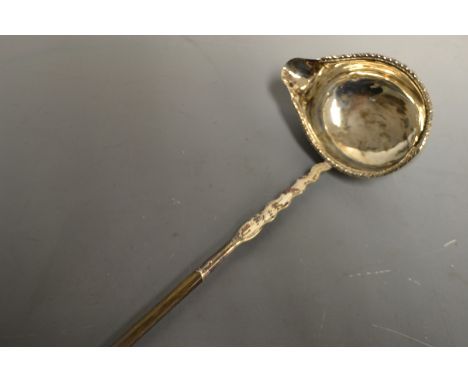 A George III silver coloured metal toddy ladle, boat shaped bowl with gadrooned border, wavy socle initialled MP, twisted wha