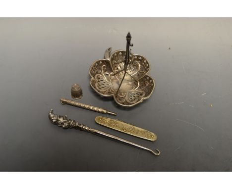 An Edwardian silver pierced dressing table tidy; a novelty silver halted Mr Punch button hook; a silver thimble; etc