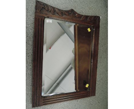 A vintage mirror with carved oak frame and bevel edged glass