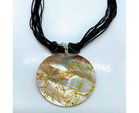 Large round mother of pearl medallion pendant decorated with golden swirls measuring 2.5"dia. The necklace is multiple strand