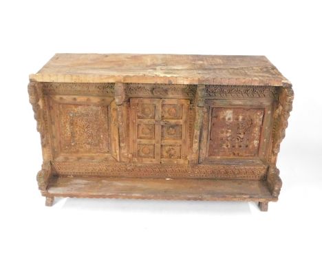 An Indian sub-Continent rustic hardwood cupboard, the front carved with reptile buttresses, metal set panels and two carved d