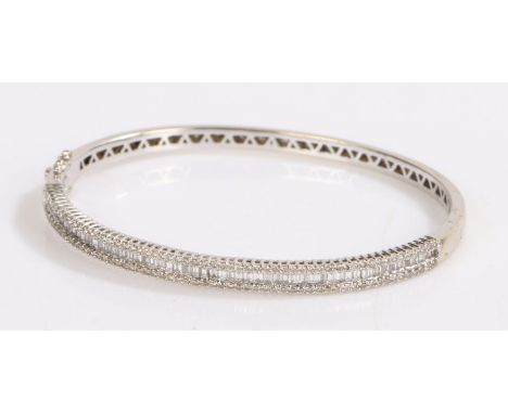 18 carat white gold diamond set bangle, with a row of baguette cut diamonds flanked to either side by rows of round cut diamo