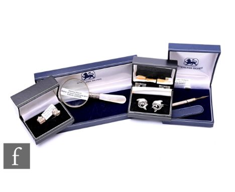 A collection of sterling silver, including novelty cufflinks, an engine turned toothpick with gold metal pick, and a magnifyi