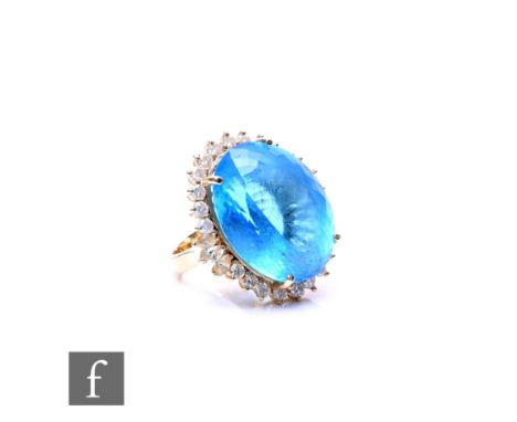 A 14ct blue topaz and diamond cluster ring, central oval topaz, length 22mm, within a border of brilliant and marquise cut di