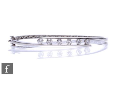 An 18ct hallmarked white gold hinged bangle, part channel set with six brilliant cut diamonds, total weight approximately 1.2