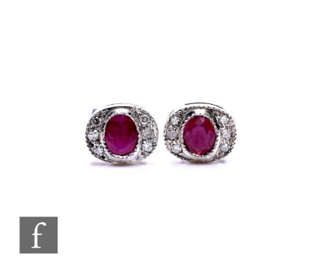 A pair of 9ct ruby and diamond set stud earrings, of oval form with central ruby surrounded by diamonds, length 0.7cm, total 