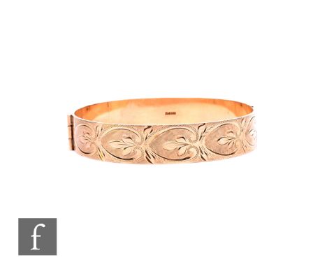A 9ct hallmarked hinged bangle with part foliate engraved decoration to front, weight 24.5g.