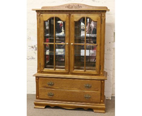 A carved oak display cabinet over single drawer raised on ogee bracket feet.