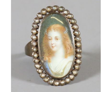 A yellow metal ring with a portrait miniature  of a young girl set under a border of seed pearls. Condition Report. To be use