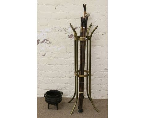 A brass and cast iron walking stick stand along with a collection of walking sticks to include carved example, thumb sticks a