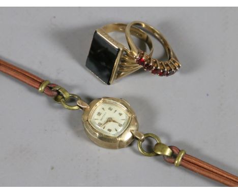 A gentleman's 9ct gold dress ring set with an onyx tablet, a ladies 9ct gold ring set with garnets, along with a ladies 9ct g