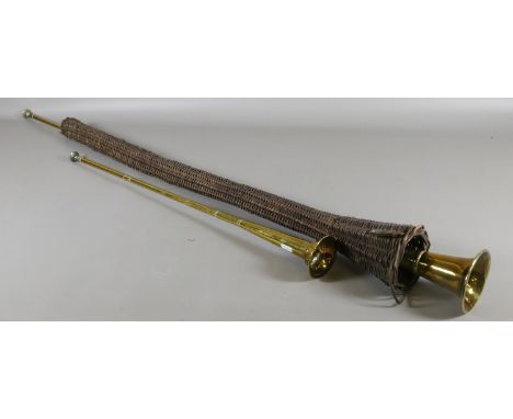 Two brass hunting horns: one in a basketware sleeve.