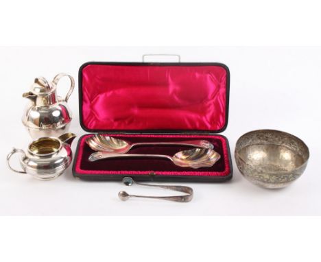 A cased pair of silver plated serving spoons with shaped bowls and shell cast finials, a plated milk jug, a plated Jersey cre