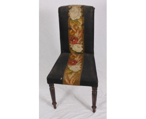 A Victorian nursing chair, the back and seat upholstered in black with central floral tapestry panel (for reupholstery)