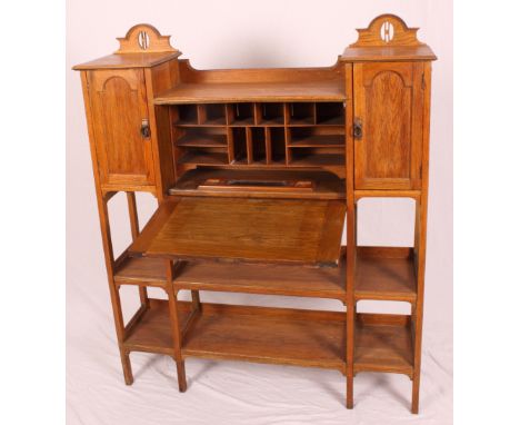 An Arts & Crafts light oak bookcase fitted two cupboards and central writing compartment, 48" wide