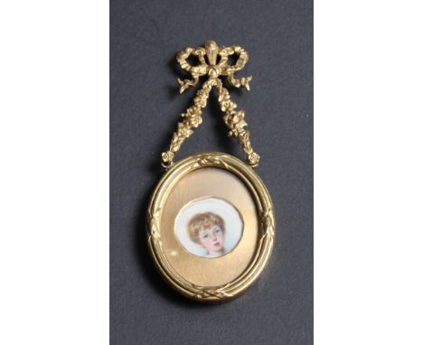 A circular miniature portrait of a young boy, in oval gilt metal frame with reed and tie border and ribbon surmount