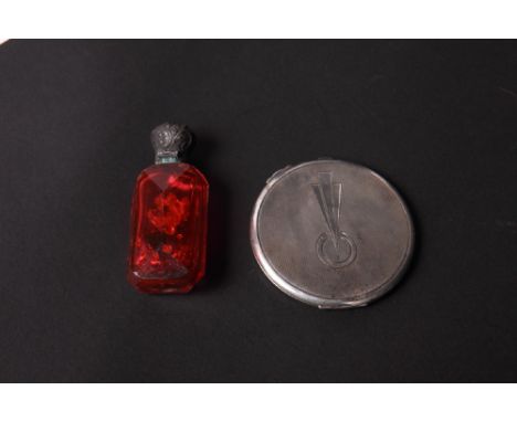 A faceted ruby glass scent bottle with embossed silver cap and an Art Deco engine turned silver compact