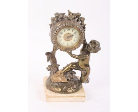 A Victorian mantel clock in gilt metal case with cherub supporter, paste set bezel, on cream marble base, 9" high