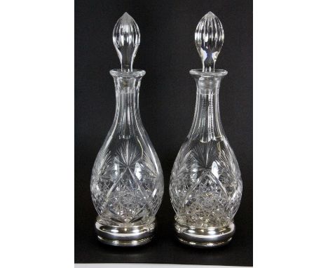 A pair of cut crystal decanters with a pair of hallmarked silver coasters H.36cm