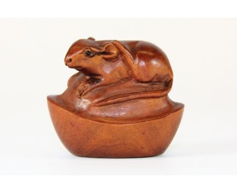A signed carved fruitwood netsuke of a mouse on a boat of cash.