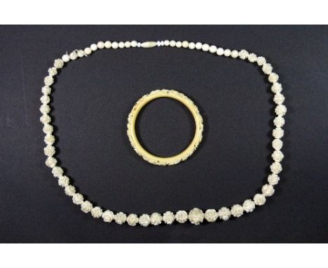 An early 20thC carved ivory bangle + ivory floral graduated beaded necklace