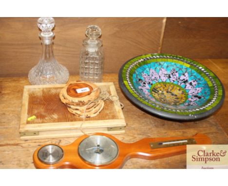 A wooden chopping board; wooden coasters; two moulded glass decanters; a barometer; and a decorative bowl