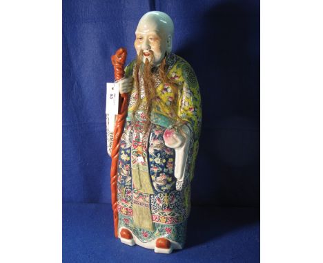 Large Chinese porcelain standing figure of an immortal with gnarled stick, overall decorated in multi coloured floral and but