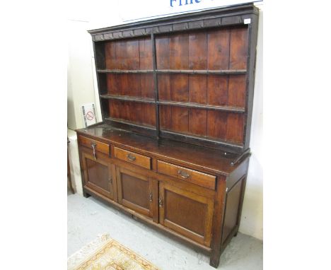 Early 19th Century Welsh oak dresser with three blind panel cupboards on stile supports.