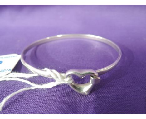 A white metal tension bangle stamped 800 having a heart shaped clasp with diamond chip decoration